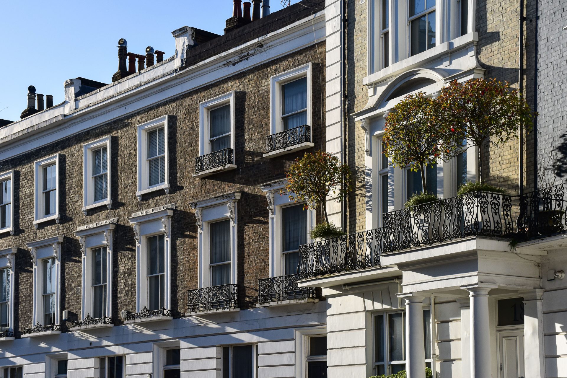 Elegant London townhouses with ornate balconies and lush greenery.